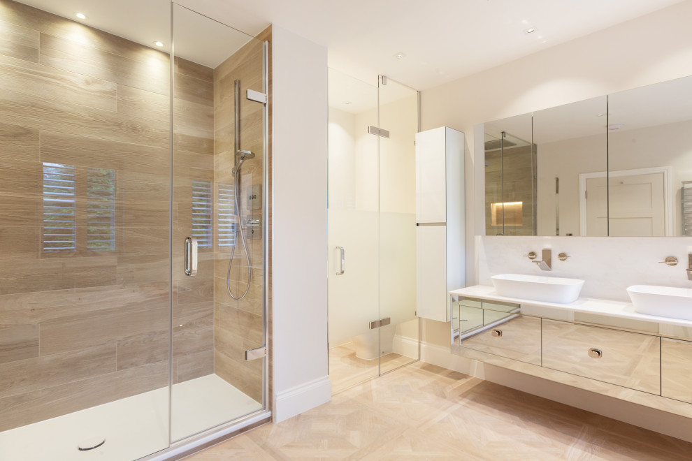 Design ideas for a mid-sized contemporary bathroom in Berkshire with glass-front cabinets, a curbless shower, a one-piece toilet, white tile, white walls, a trough sink, a hinged shower door, white benchtops, a double vanity and a floating vanity.