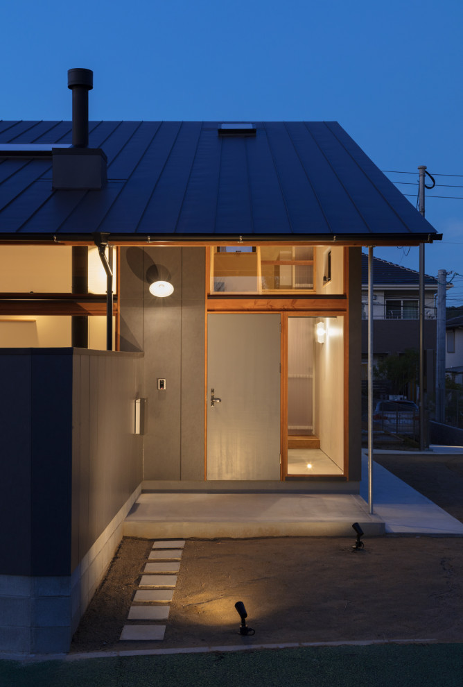 Small scandinavian two-storey black house exterior in Fukuoka with a shed roof, a metal roof, a black roof and board and batten siding.