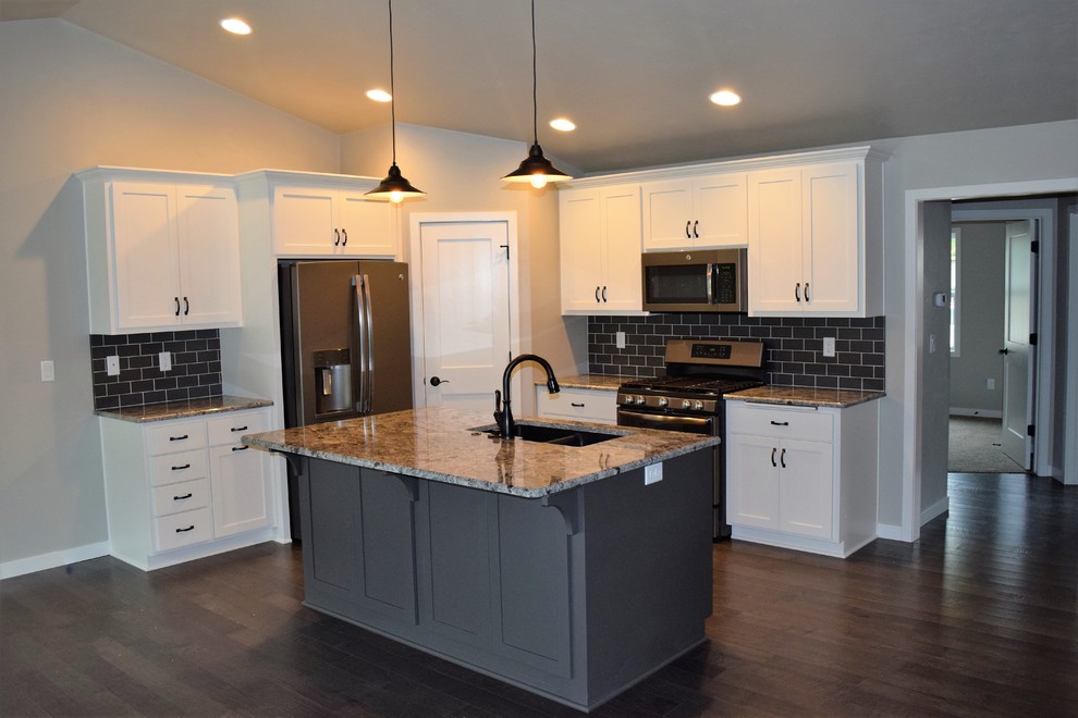 Mountain style kitchen photo with white cabinets, stainless steel appliances and an island