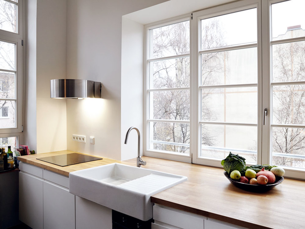 Diseño de cocinas en L moderna grande abierta con fregadero integrado, puertas de armario blancas, encimera de madera, suelo de ladrillo y suelo rojo