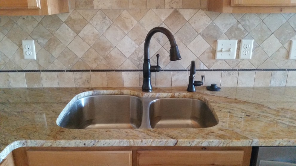 Inspiration for a mid-sized rustic l-shaped concrete floor kitchen pantry remodel in Austin with light wood cabinets, granite countertops, beige backsplash, stone tile backsplash, stainless steel appliances, an undermount sink, recessed-panel cabinets and an island
