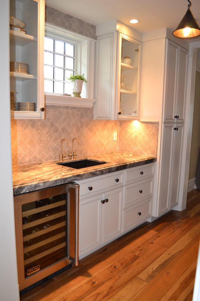 This is an example of a country kitchen in San Francisco with an undermount sink, beaded inset cabinets, white cabinets, marble benchtops, grey splashback, stone tile splashback and medium hardwood floors.
