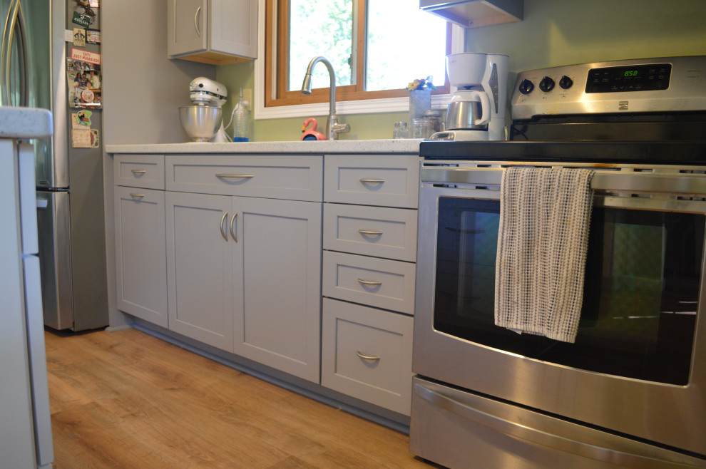 Example of a small transitional single-wall vinyl floor eat-in kitchen design with an undermount sink, shaker cabinets, gray cabinets, solid surface countertops, stainless steel appliances, an island and white countertops