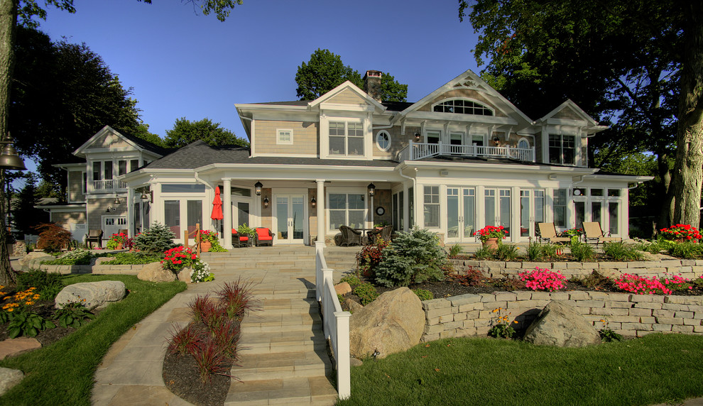 This is an example of an expansive traditional two-storey beige house exterior in Other with wood siding and a shingle roof.