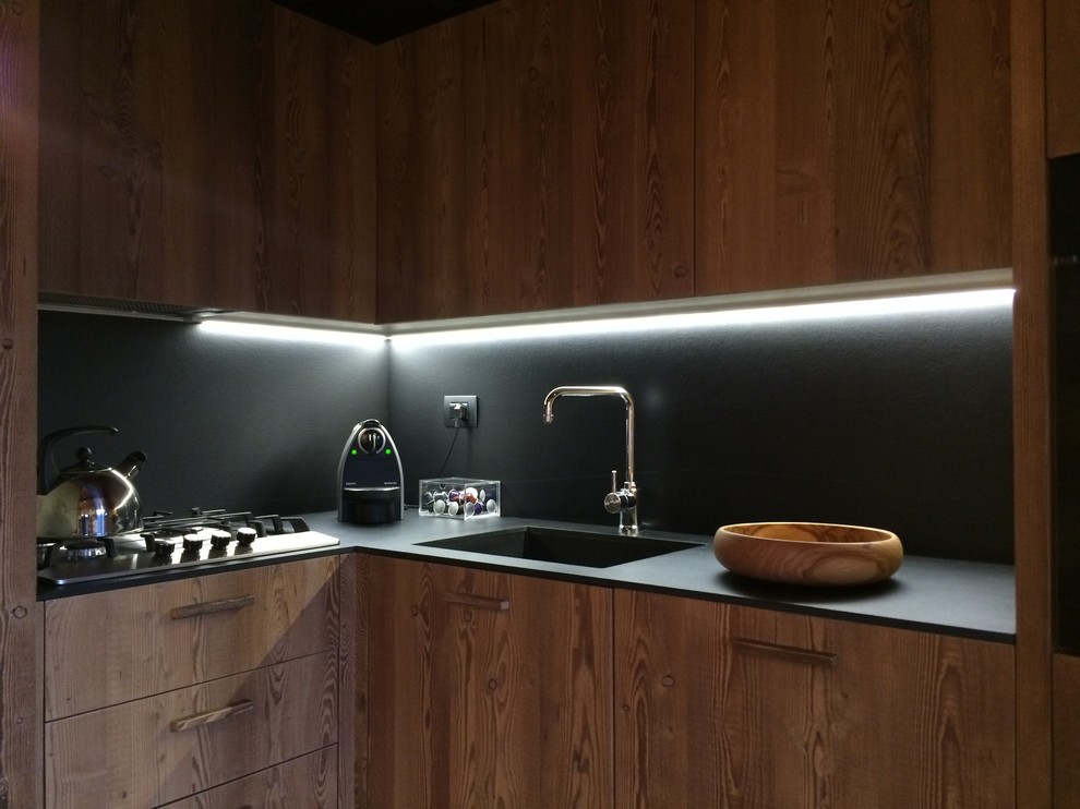 Mid-sized country l-shaped open plan kitchen in Turin with an integrated sink, flat-panel cabinets, medium wood cabinets, no island, ceramic floors, black splashback and black appliances.