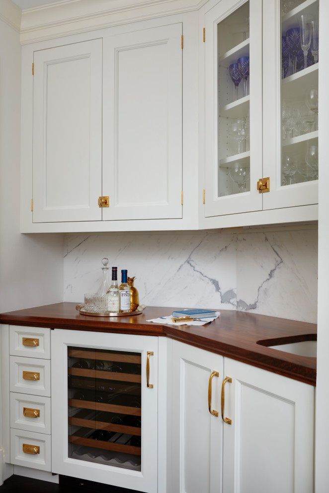 Traditional single-wall home bar in New York with a submerged sink, recessed-panel cabinets, white cabinets, marble worktops, white splashback, marble splashback, medium hardwood flooring, brown floors and white worktops.