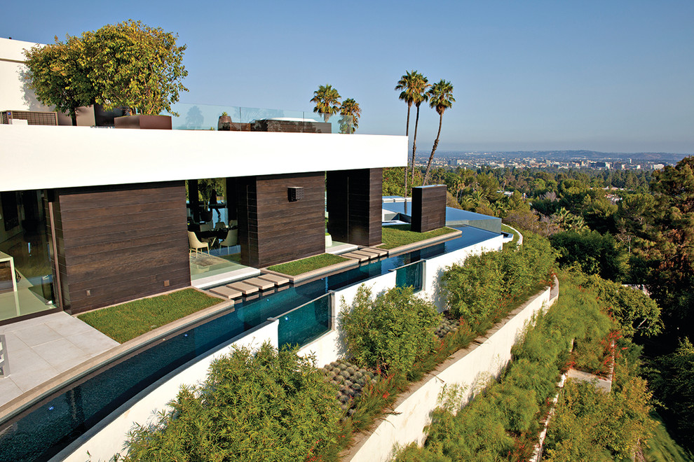 Expansive modern backyard custom-shaped infinity pool in Los Angeles with with a pool and tile.
