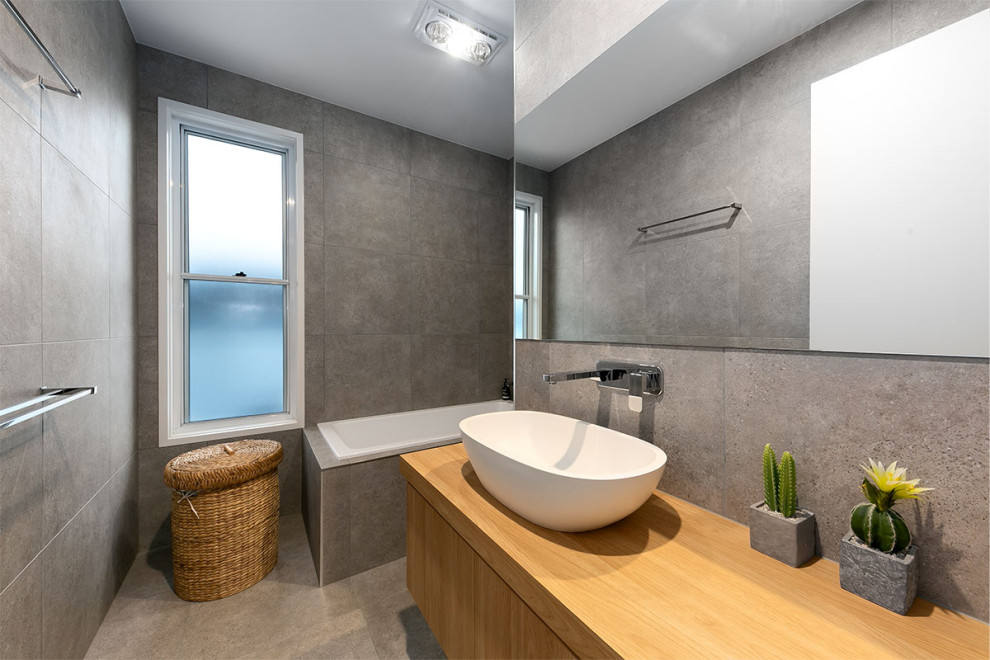 Inspiration for a mid-sized contemporary master bathroom in Sunshine Coast with flat-panel cabinets, medium wood cabinets, a drop-in tub, gray tile, a vessel sink, wood benchtops, grey floor, brown benchtops and a floating vanity.