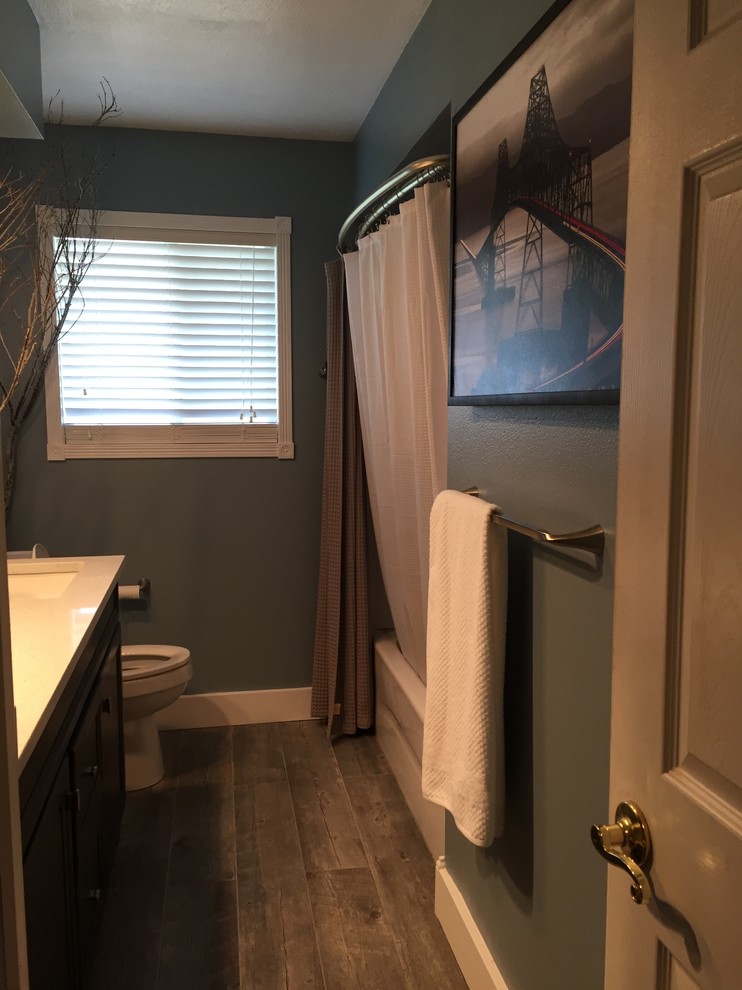 Photo of a small industrial kids bathroom in Portland with recessed-panel cabinets, grey cabinets, an alcove tub, blue tile, porcelain floors, an undermount sink, quartzite benchtops and a shower curtain.