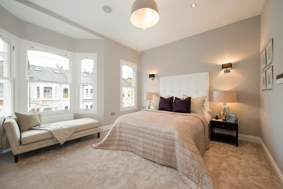 Photo of a large transitional master bedroom in London with grey walls and carpet.