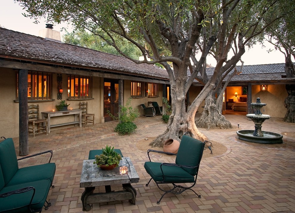 Photo of a large courtyard patio in Santa Barbara with a water feature, brick pavers and no cover.
