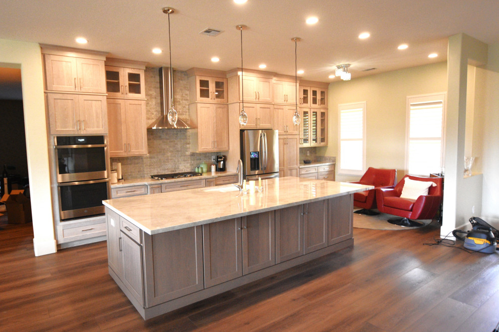 Large transitional vinyl floor kitchen photo with an undermount sink, shaker cabinets, light wood cabinets, quartzite countertops, multicolored backsplash, porcelain backsplash, stainless steel appliances, an island and beige countertops