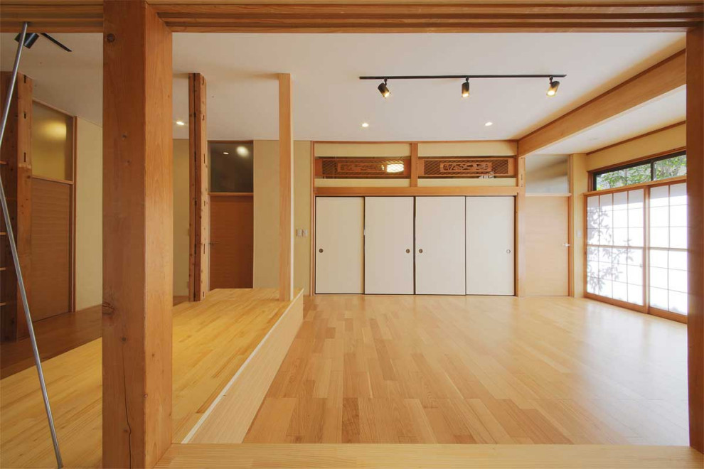 Asiatisk inredning av ett mellanstort separat vardagsrum, med ett bibliotek, beige väggar, plywoodgolv och en fristående TV