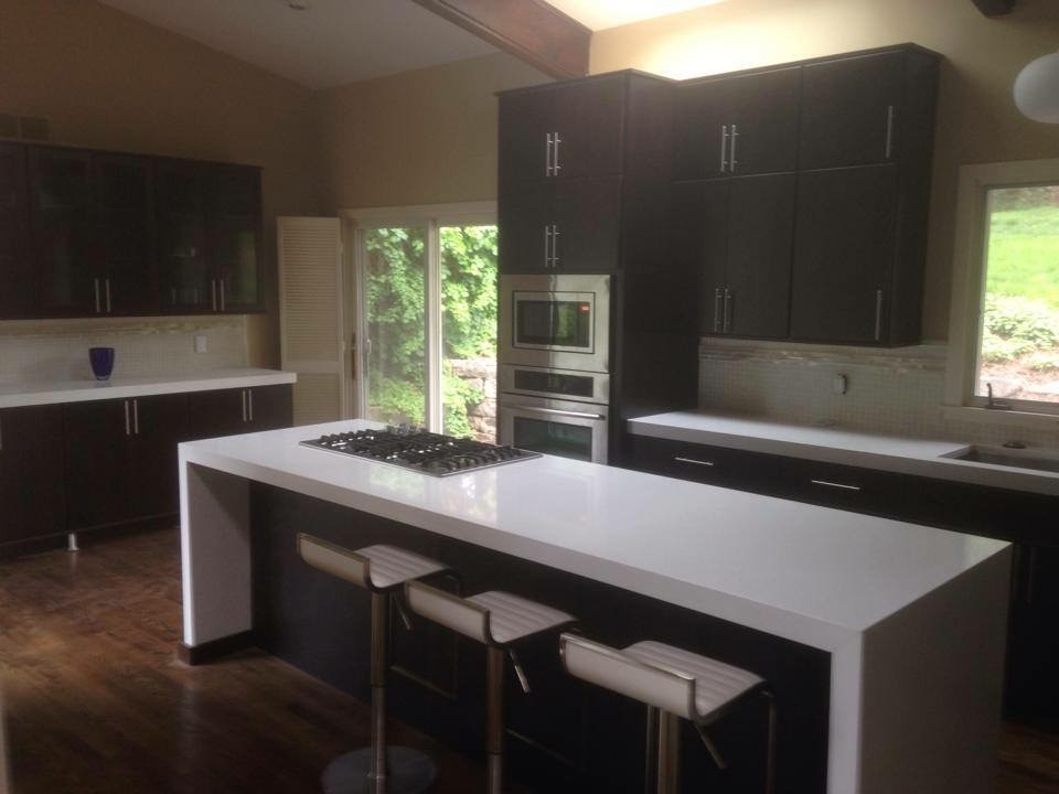 Kitchen - mid-sized transitional galley medium tone wood floor kitchen idea with an undermount sink, flat-panel cabinets, dark wood cabinets, quartz countertops, white backsplash, mosaic tile backsplash, stainless steel appliances and an island