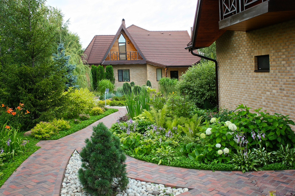 This is an example of a mid-sized mediterranean courtyard partial sun driveway for summer in Moscow with brick pavers and a garden path.