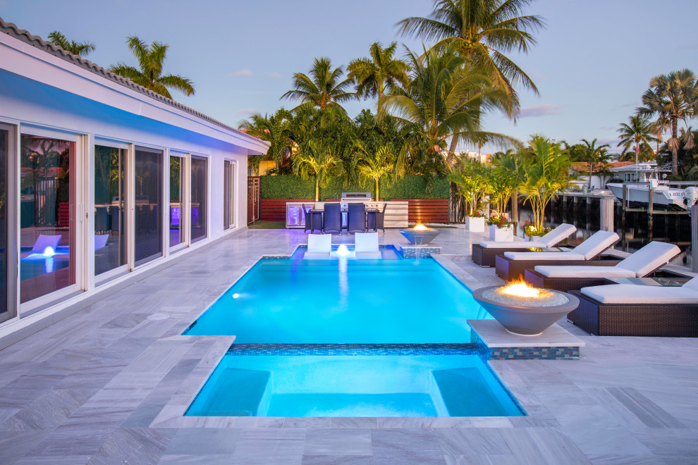 Photo of a mid-sized modern backyard rectangular lap pool in Miami with a water feature.