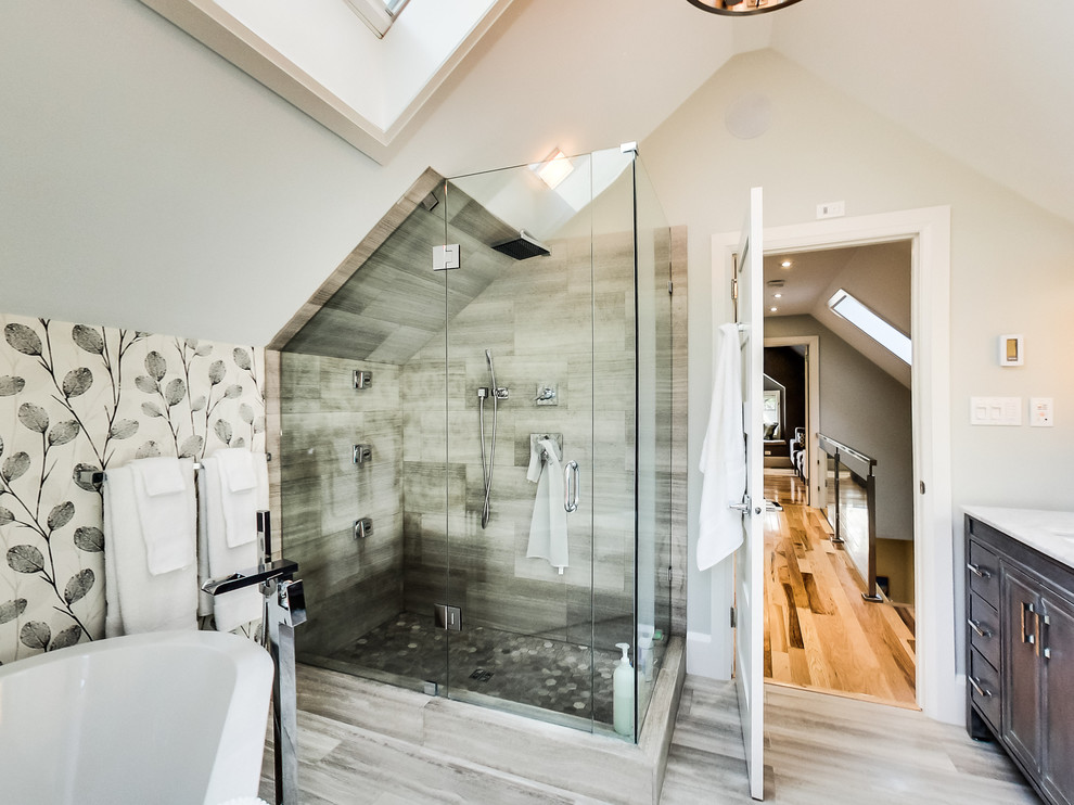Large transitional master gray tile and limestone tile limestone floor and gray floor freestanding bathtub photo in Toronto with furniture-like cabinets, gray cabinets, a two-piece toilet, white walls, an undermount sink, quartz countertops and a hinged shower door