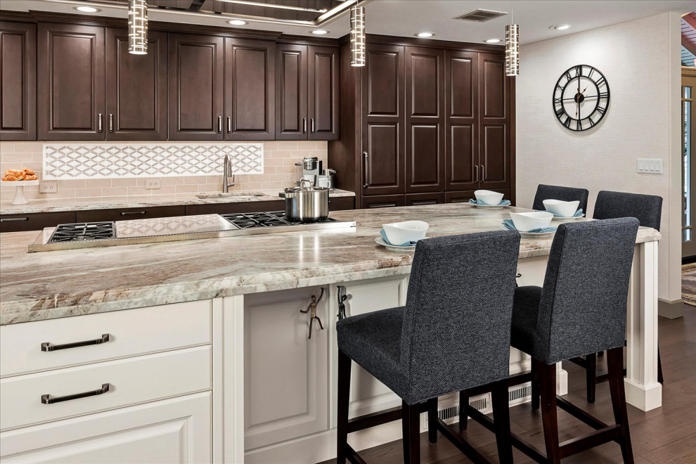 Huge transitional l-shaped medium tone wood floor and brown floor open concept kitchen photo in Seattle with an undermount sink, raised-panel cabinets, brown cabinets, quartzite countertops, beige backsplash, porcelain backsplash, stainless steel appliances, an island and multicolored countertops