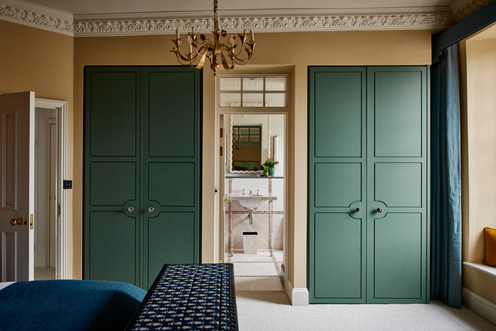 Photo of a traditional built-in wardrobe in Wiltshire with flat-panel cabinets, green cabinets, carpet and grey floor.