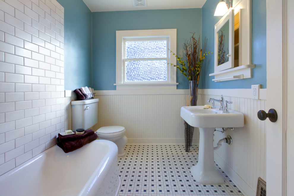 This is an example of a traditional bathroom in Los Angeles with a freestanding tub, a two-piece toilet, white tile, subway tile, blue walls, mosaic tile floors, a pedestal sink and white floor.