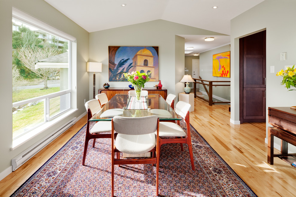 This is an example of a transitional dining room in Vancouver with medium hardwood floors and grey walls.