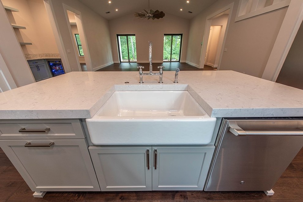 This is an example of a country l-shaped kitchen in Tampa with a farmhouse sink, stainless steel appliances, dark hardwood floors and with island.
