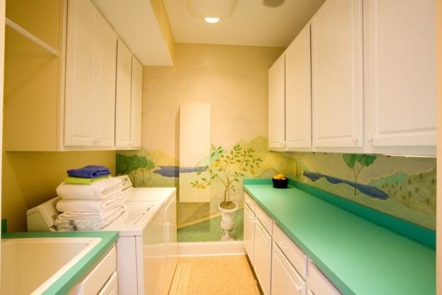 Mid-sized contemporary galley dedicated laundry room in Columbus with a drop-in sink, raised-panel cabinets, white cabinets, solid surface benchtops, yellow walls, light hardwood floors, a side-by-side washer and dryer and beige floor.