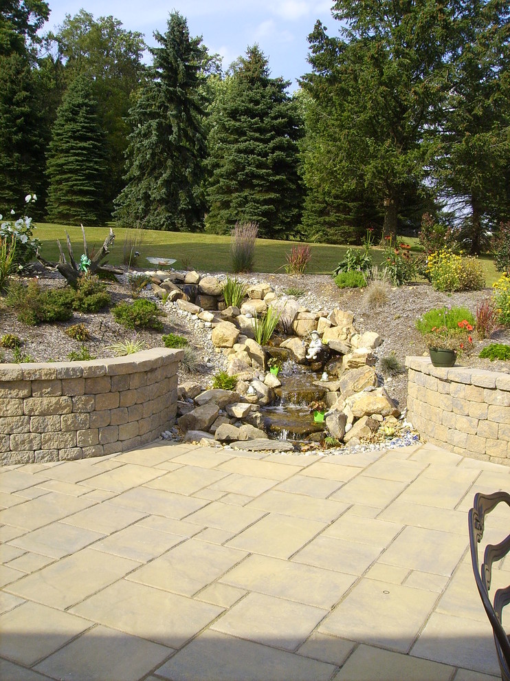 Inspiration for a traditional backyard patio in Other with a water feature and concrete pavers.
