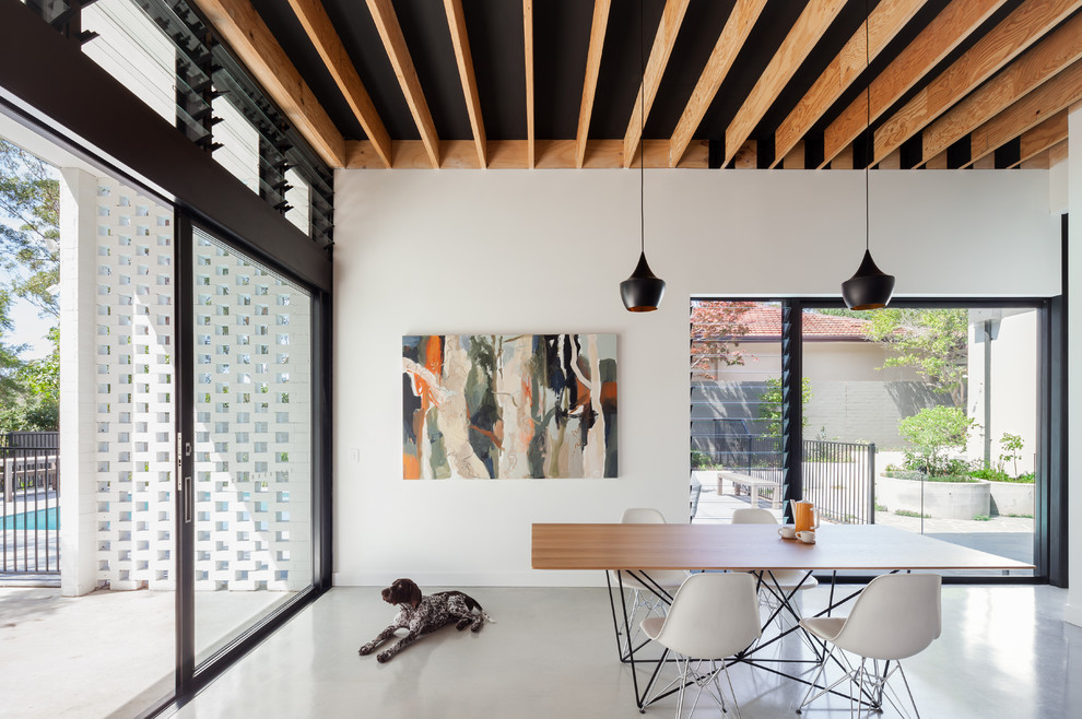 This is an example of a large contemporary dining room in Sydney with white walls and concrete floors.