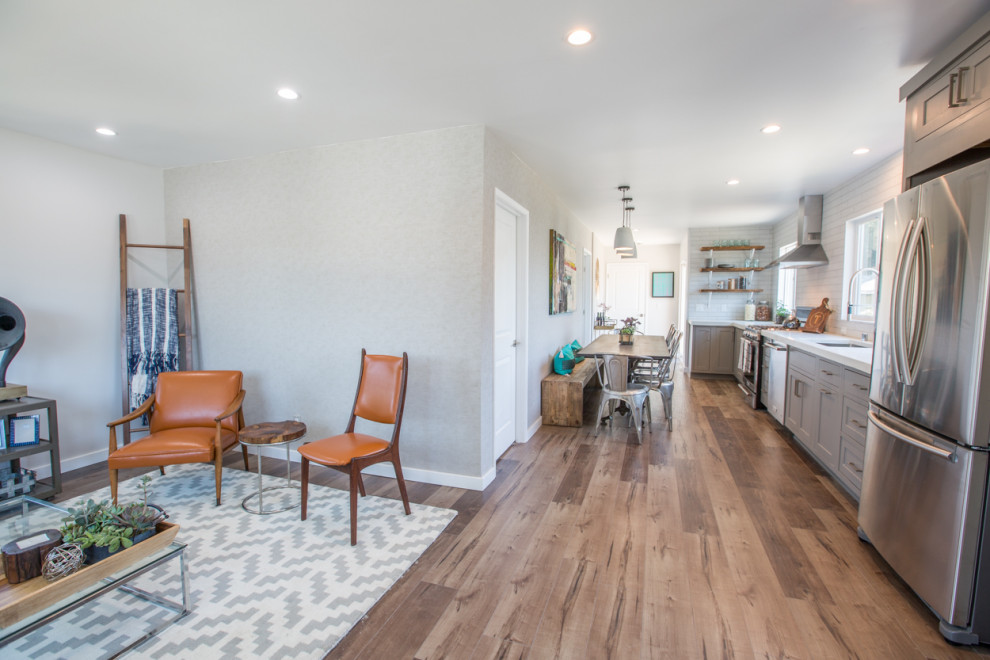 Photo of a small country l-shaped eat-in kitchen in Los Angeles with medium hardwood floors, brown floor, an undermount sink, shaker cabinets, grey cabinets, solid surface benchtops, white splashback, subway tile splashback, stainless steel appliances, no island and white benchtop.