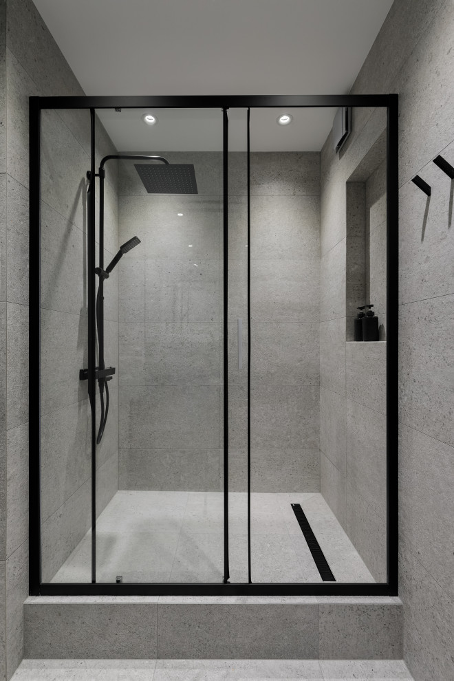 Photo of a mid-sized contemporary 3/4 bathroom in Saint Petersburg with flat-panel cabinets, medium wood cabinets, an alcove shower, a wall-mount toilet, black tile, porcelain tile, grey walls, porcelain floors, a drop-in sink, engineered quartz benchtops, grey floor, a sliding shower screen, black benchtops, a single vanity and a freestanding vanity.