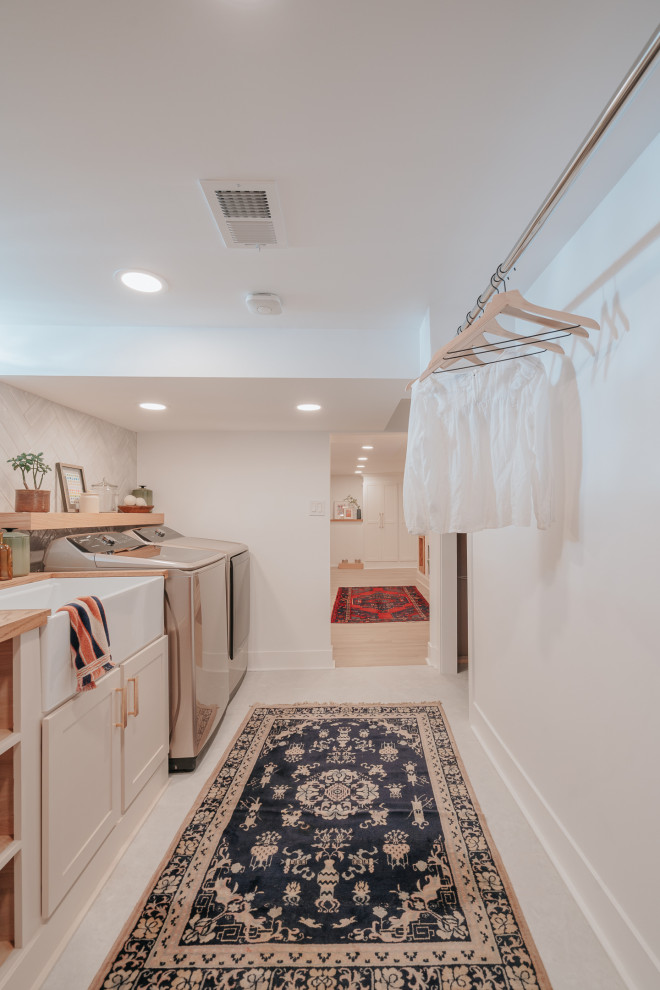 Small modern galley dedicated laundry room in Detroit with a farmhouse sink, shaker cabinets, beige cabinets, wood benchtops, a side-by-side washer and dryer and brown benchtop.