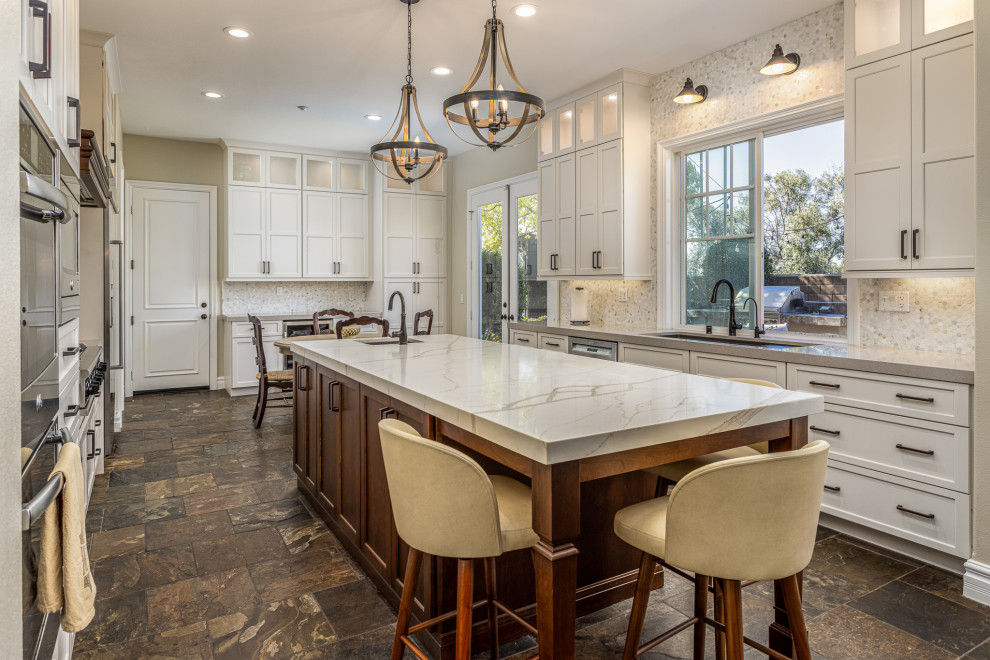 Eat-in kitchen - large coastal u-shaped eat-in kitchen idea in San Diego with a double-bowl sink, shaker cabinets, white cabinets, quartz countertops, white backsplash, porcelain backsplash, stainless steel appliances, an island and white countertops