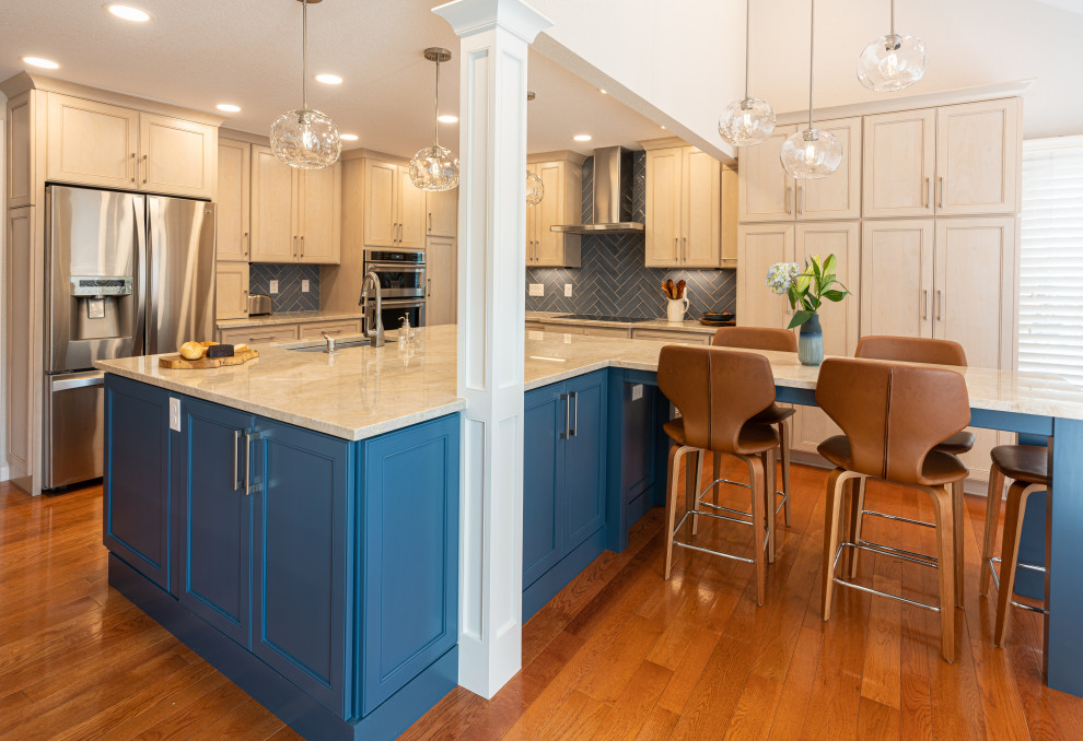 This is an example of a mid-sized transitional l-shaped eat-in kitchen in Denver with a single-bowl sink, flat-panel cabinets, blue cabinets, quartzite benchtops, blue splashback, porcelain splashback, stainless steel appliances, medium hardwood floors, with island, brown floor, beige benchtop and vaulted.