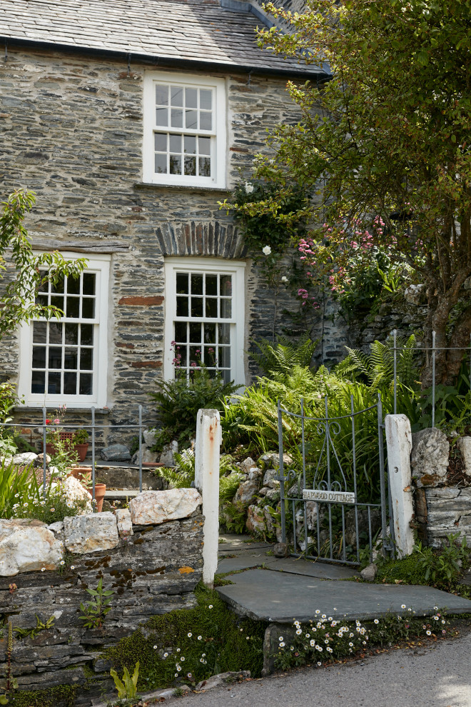 This is an example of a traditional front yard garden in Cornwall with with a gate and natural stone pavers.