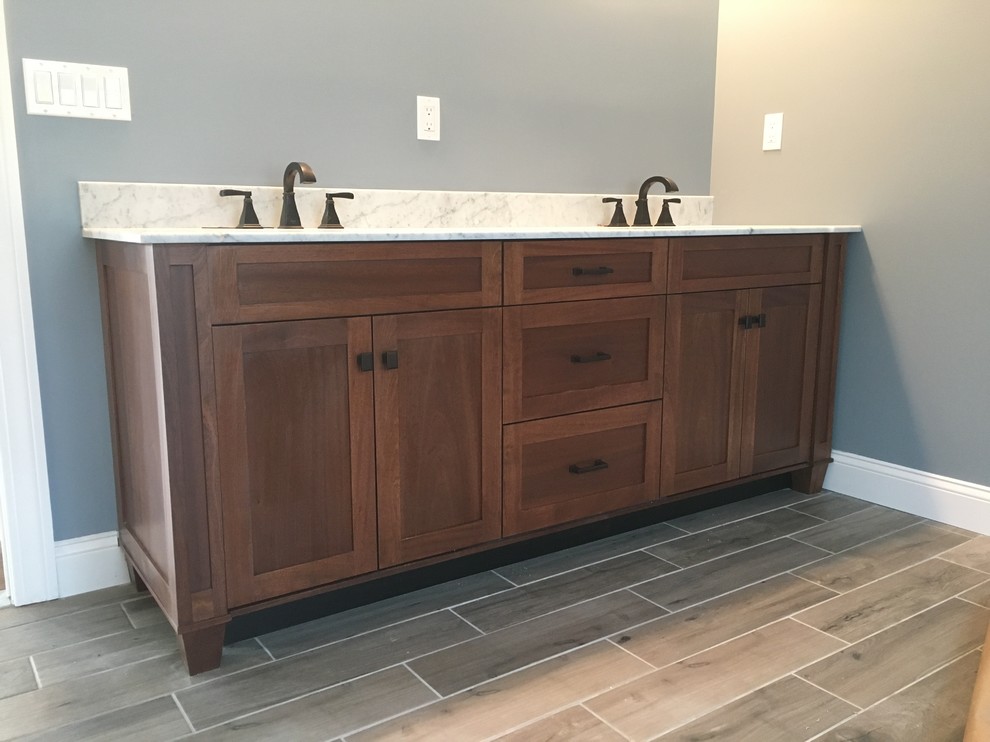 This is an example of a large arts and crafts master bathroom in New York with shaker cabinets, medium wood cabinets, grey walls, ceramic floors and marble benchtops.