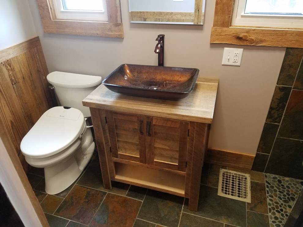 Small country 3/4 bathroom in Cincinnati with louvered cabinets, light wood cabinets, a curbless shower, a bidet, multi-coloured tile, slate, beige walls, slate floors, a vessel sink, multi-coloured floor, an open shower and wood benchtops.