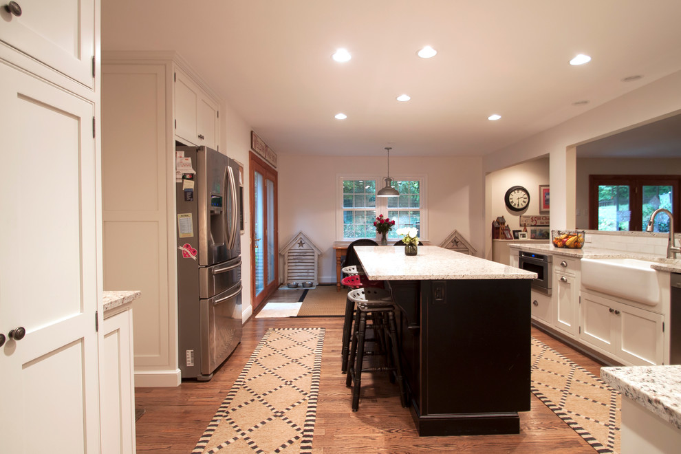 Eat-in kitchen - transitional u-shaped eat-in kitchen idea in DC Metro with a farmhouse sink, beaded inset cabinets, white cabinets, granite countertops, white backsplash, subway tile backsplash and stainless steel appliances