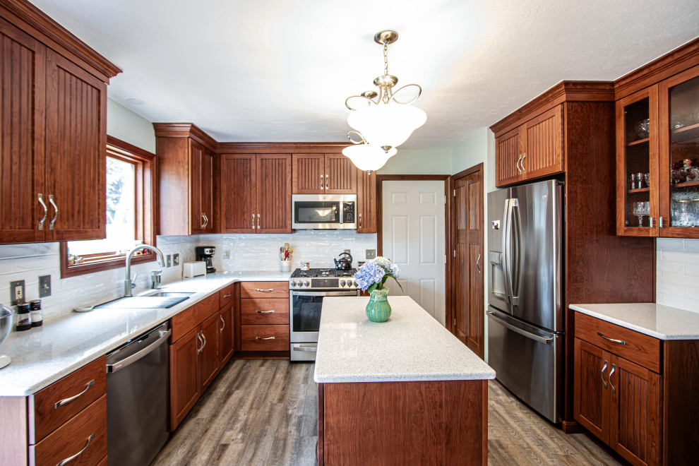 This is an example of a mid-sized transitional galley eat-in kitchen in Cleveland with an undermount sink, beaded inset cabinets, medium wood cabinets, quartz benchtops, white splashback, subway tile splashback, stainless steel appliances, vinyl floors, with island, grey floor and beige benchtop.