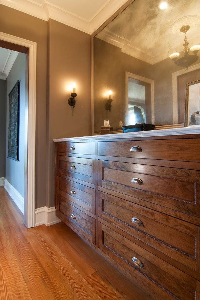 Design ideas for a mid-sized traditional gender-neutral dressing room in San Francisco with recessed-panel cabinets, medium wood cabinets and light hardwood floors.