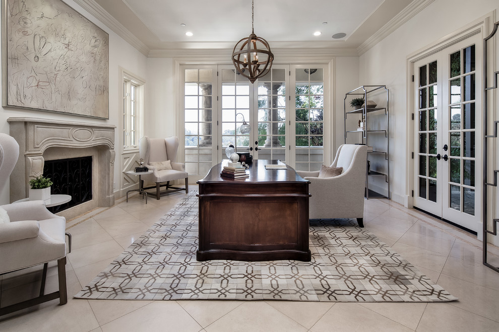Mediterranean study room in Los Angeles with white walls, a standard fireplace, a stone fireplace surround, a freestanding desk and beige floor.