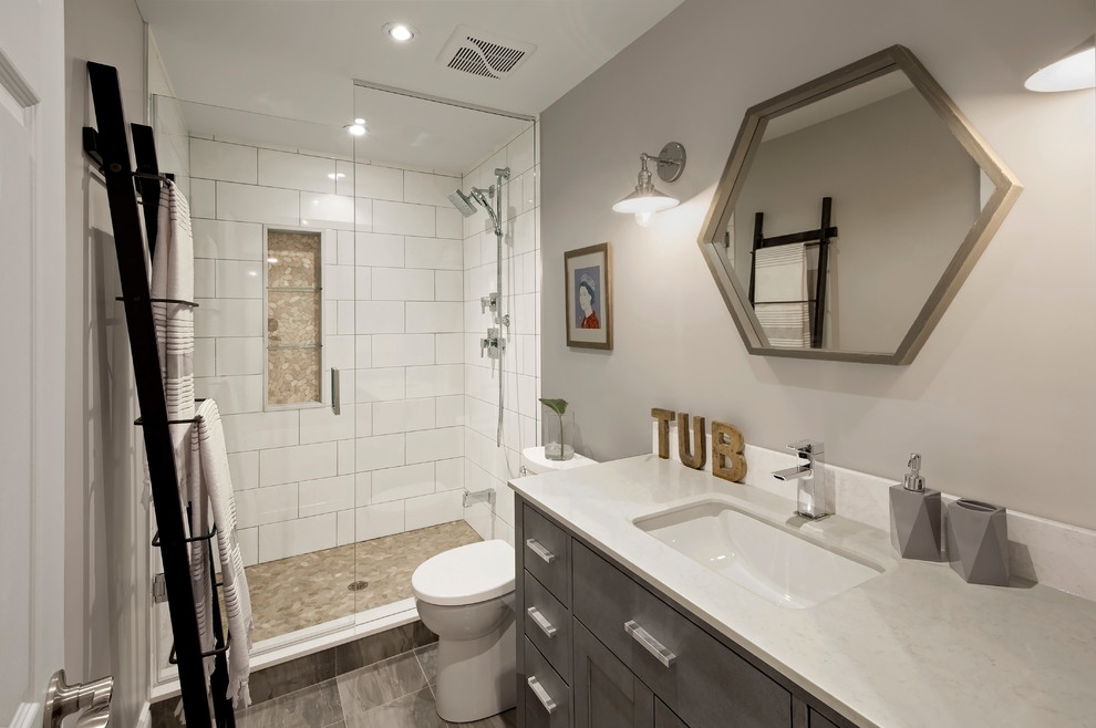 Design ideas for a mid-sized contemporary 3/4 bathroom in Toronto with grey walls, beaded inset cabinets, grey cabinets, an alcove shower, a one-piece toilet, white tile, porcelain tile, porcelain floors, an undermount sink, engineered quartz benchtops, grey floor and a hinged shower door.