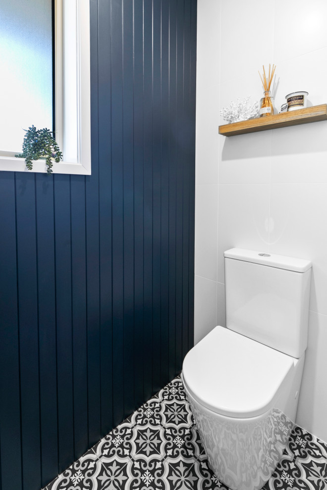 Photo of a small coastal cloakroom in Sydney with freestanding cabinets, medium wood cabinets, a two-piece toilet, white tiles, porcelain tiles, blue walls, porcelain flooring, an integrated sink, solid surface worktops, blue floors, white worktops, a floating vanity unit and tongue and groove walls.