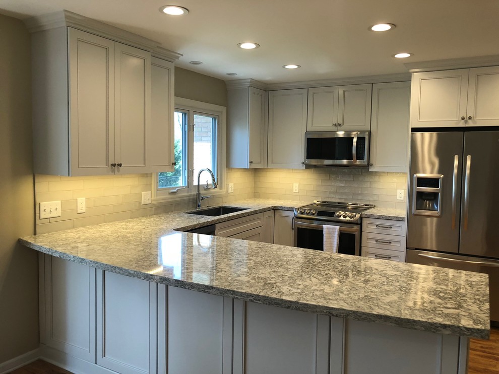 This is an example of a mid-sized transitional u-shaped open plan kitchen in Other with an undermount sink, recessed-panel cabinets, white cabinets, quartz benchtops, stainless steel appliances, medium hardwood floors and green benchtop.