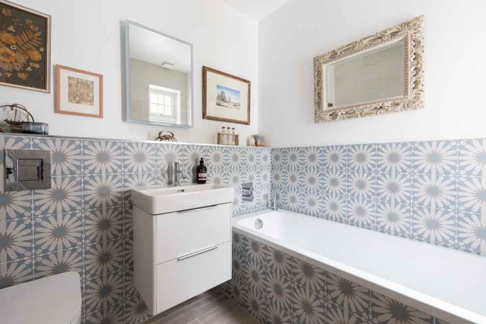 Bild på ett funkis badrum, med släta luckor, vita skåp, flerfärgad kakel, vita väggar, ett konsol handfat och grått golv