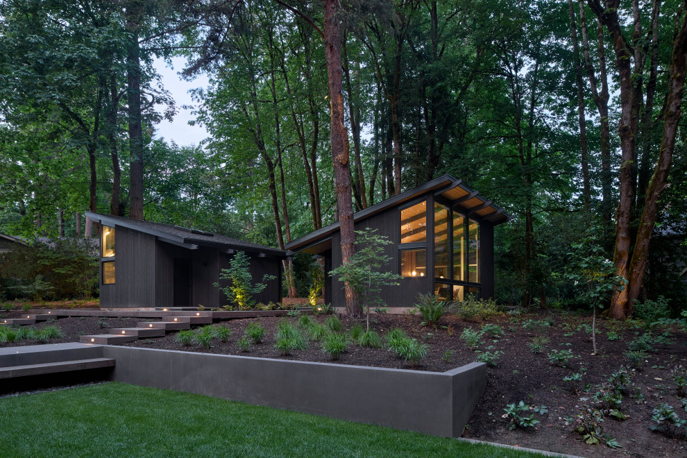 Inspiration for a large midcentury one-storey black house exterior in Portland with wood siding, a shed roof, a shingle roof and a black roof.