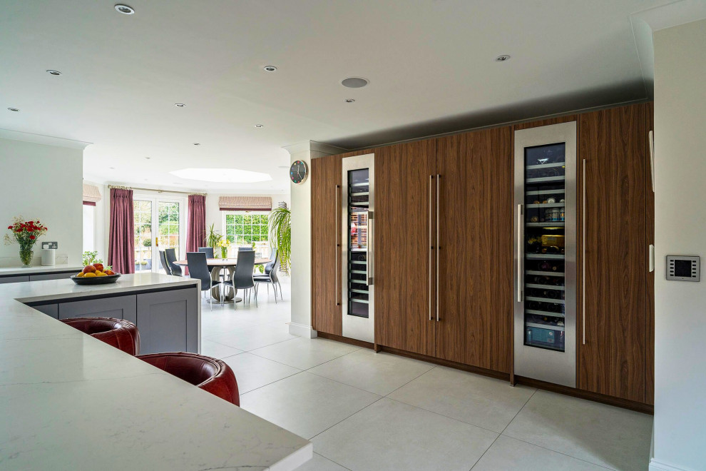 Photo of a medium sized classic l-shaped open plan kitchen in Oxfordshire with a single-bowl sink, recessed-panel cabinets, grey cabinets, marble worktops, black appliances, an island, grey floors and white worktops.