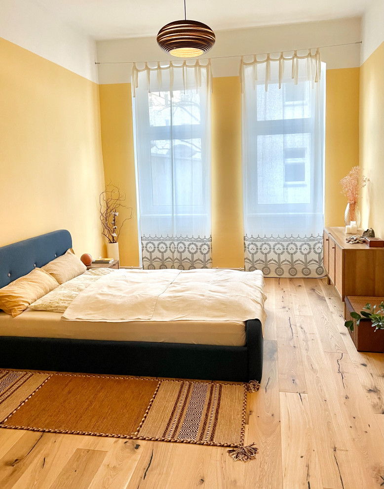 Foto de dormitorio principal nórdico de tamaño medio con paredes amarillas, suelo de madera clara y suelo marrón