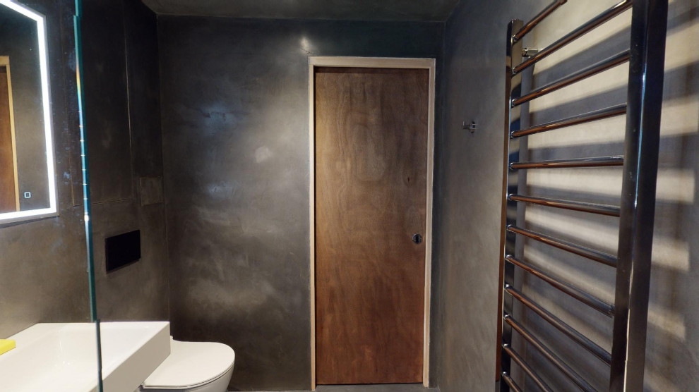 Foto på ett mellanstort funkis badrum för barn, med släta luckor, vita skåp, ett platsbyggt badkar, en dusch/badkar-kombination, en vägghängd toalettstol, grå väggar, betonggolv och grått golv