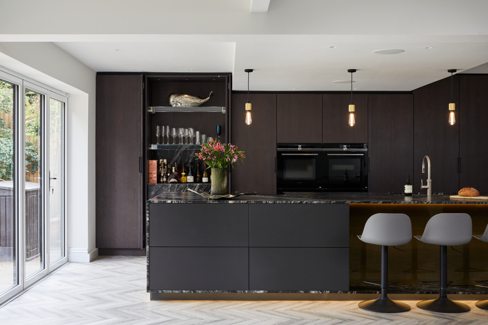 Idéer för ett stort modernt svart linjärt kök med öppen planlösning, med en undermonterad diskho, släta luckor, granitbänkskiva, rostfria vitvaror, ljust trägolv, en köksö och grått golv